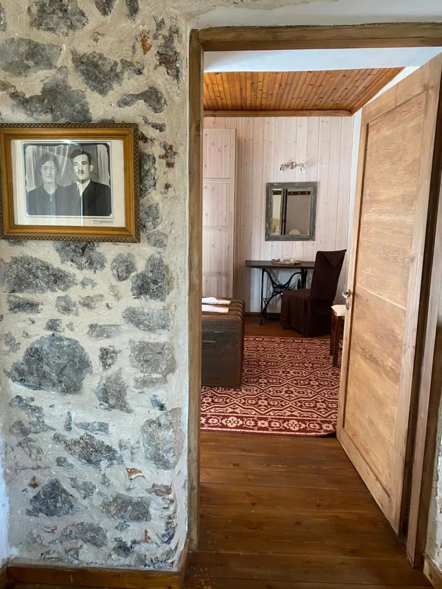 Πέτρινος τοίχος με παλιά οικογενειακή φωτογραφία και πόρτα προς το υπνοδωμάτιο